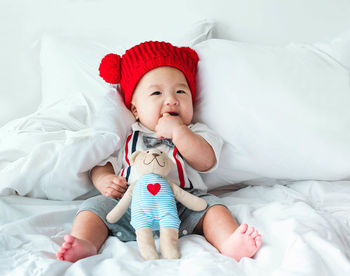 Baby boy with stuffed toy on bed at home