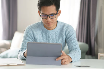 Mid adult man using mobile phone while sitting on table