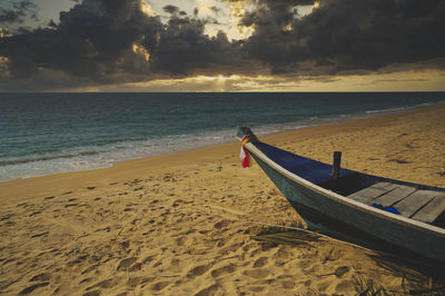 Boat on beach against sky during sunset