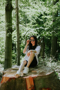 Young woman sitting on rock in forest