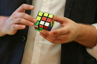 Midsection of man playing with puzzle cube