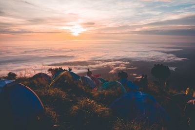 Tents on mountain peak against sky during sunset