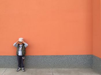 Full length of cute boy standing against wall