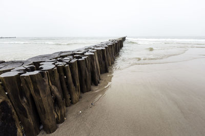 Wooden posts on beach against sky