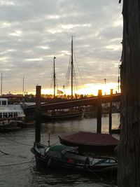 Boats in harbor against cloudy sky