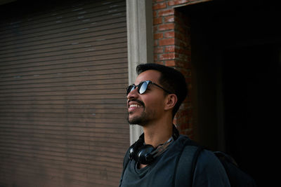 Portrait of young man looking away against wall