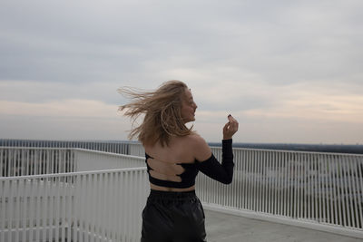 Full length of woman standing by railing against sea