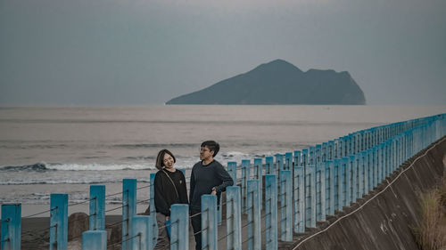 Rear view of woman standing by sea against sky