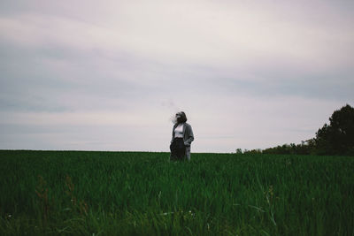 Woman standing amidst crops on agricultural field against sky