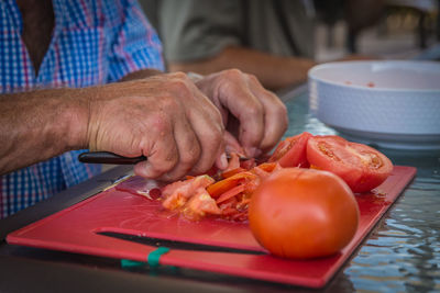 Midsection of man cutting tomatoes at table