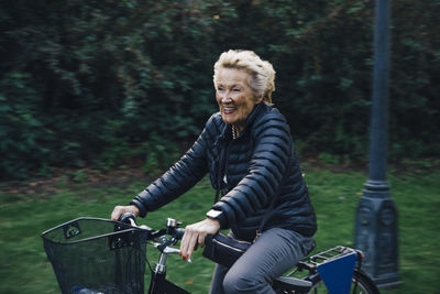 Smiling senior woman riding bicycle in park