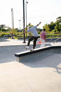 Rear view of man skateboarding on skateboard against sky