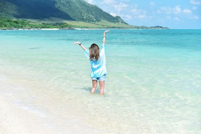 Full length rear view of woman standing on beach