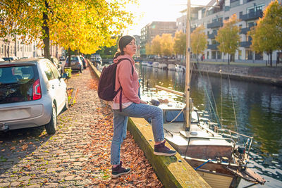 Young woman stands on the bank of a canal in the old town at the autumn. copenhagen, denmark