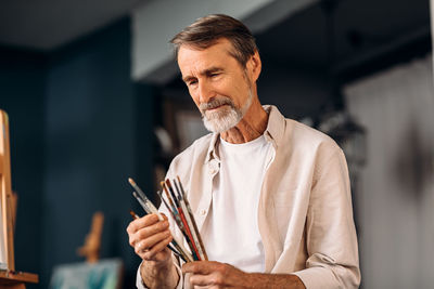 Midsection of man holding camera while standing at home