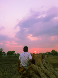 Rear view of man on field against sky during sunset