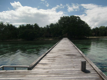 Island pier over water by ocean against sky