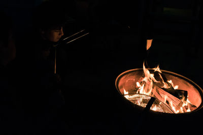 Reflection of man photographing in illuminated fire