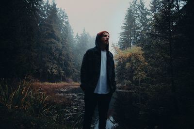 Woman standing in forest against sky