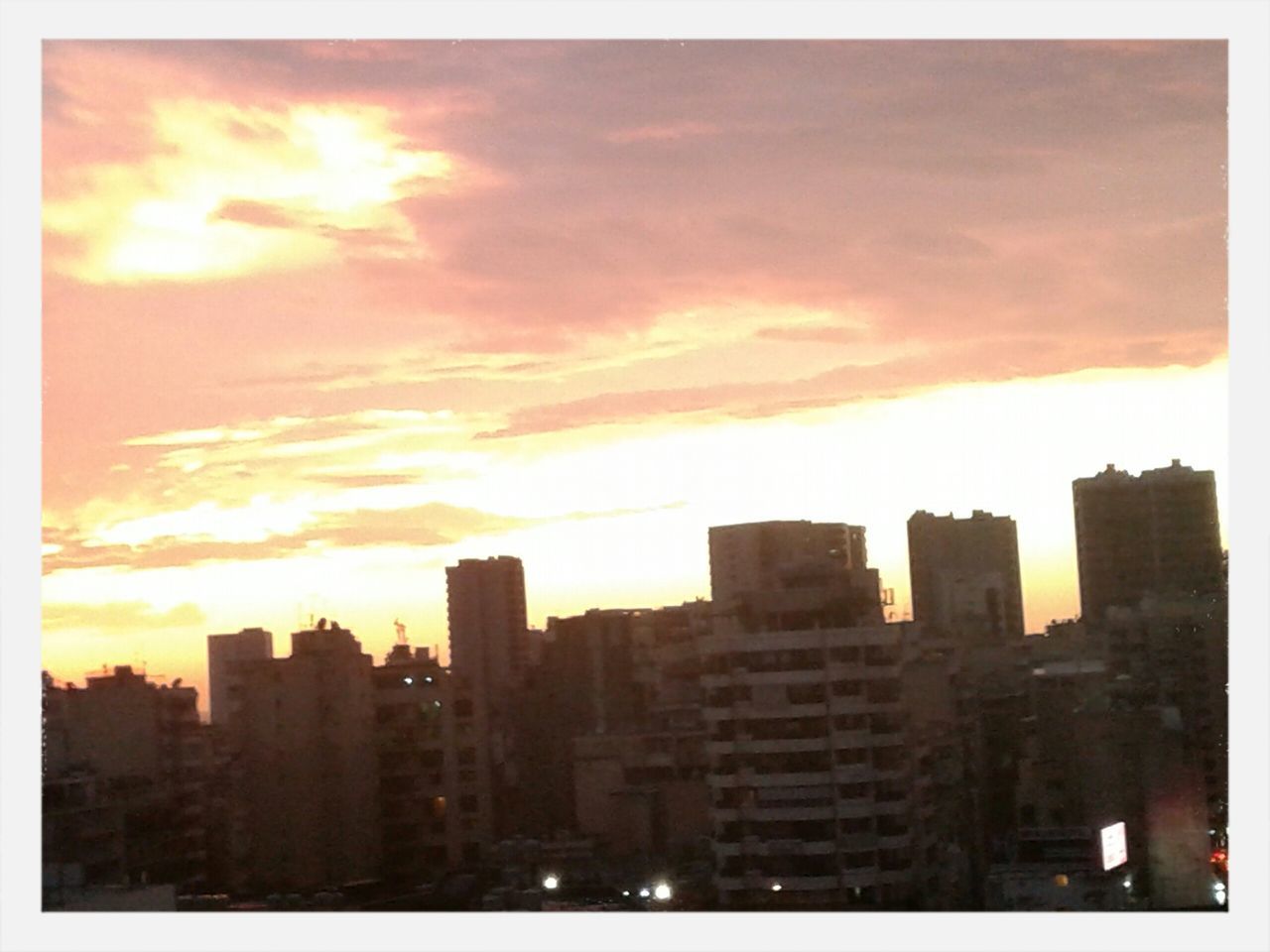 building exterior, architecture, built structure, sunset, city, transfer print, sky, silhouette, auto post production filter, cloud - sky, cityscape, building, residential building, orange color, residential structure, sun, skyscraper, outdoors, low angle view, dusk