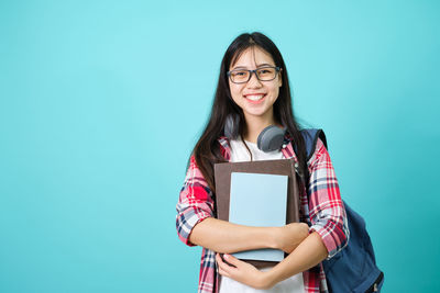 Portrait of a smiling young woman against blue background