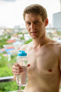 Portrait of shirtless man drinking glass