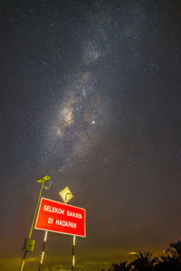 Low angle view of road sign against sky at night