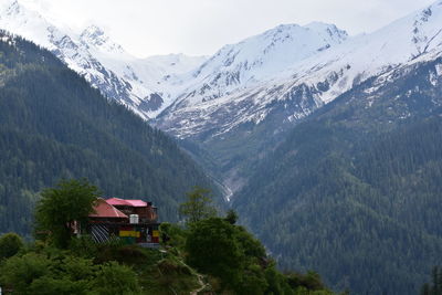 Scenic view of trees and snowcapped mountains against sky