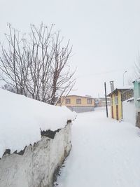 Bare tree and houses against clear sky during winter
