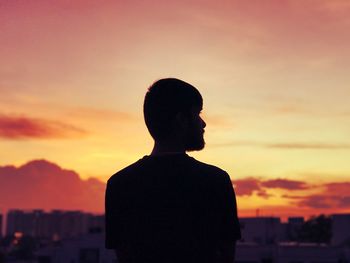Rear view of silhouette man standing against orange sky