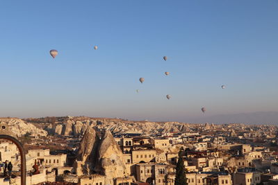 View of hot air balloons flying over buildings in city
