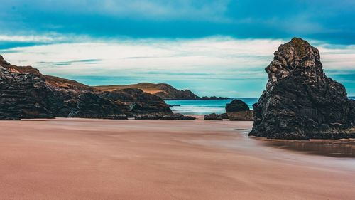 Rock formations on beach against sky