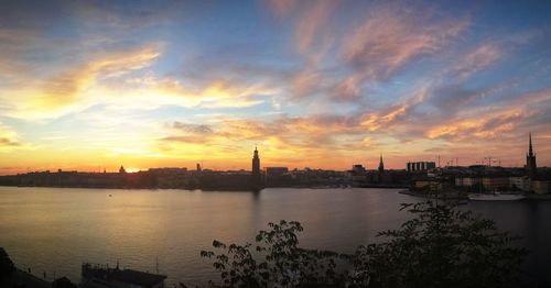 Scenic view of river by buildings against sky during sunset