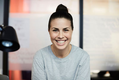 Portrait of smiling businesswoman sitting in creative office