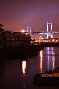 Illuminated yokohama bay bridge over sea against sky