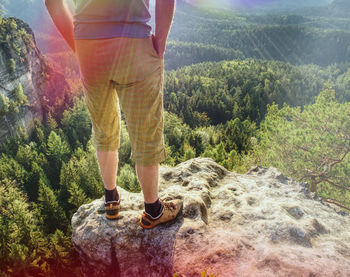 Hiker man stays on the mountain hill during hiking. hker staying on rock and looking down to valley