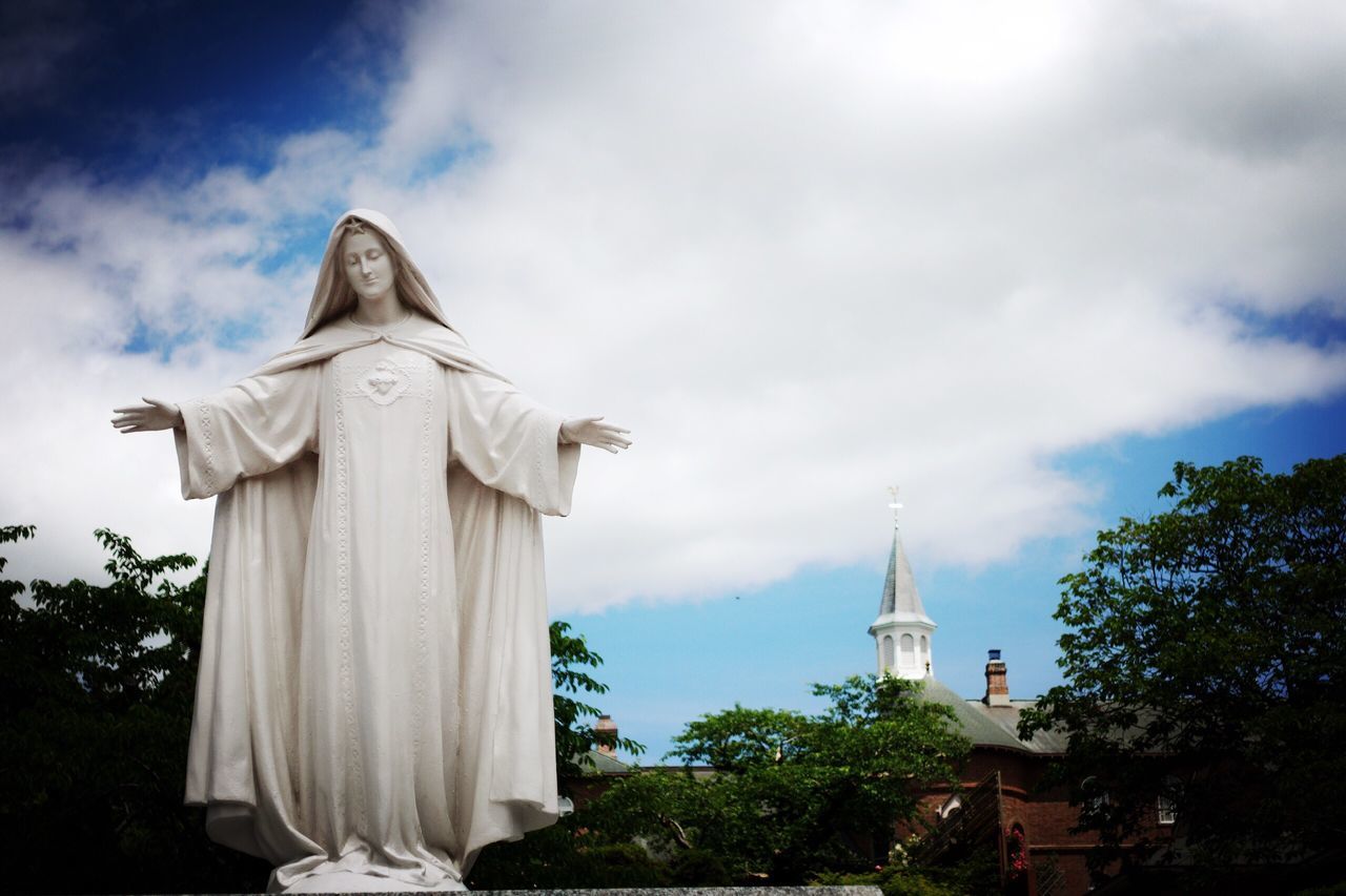 low angle view, statue, sky, architecture, religion, built structure, art and craft, cloud - sky, human representation, sculpture, cloudy, building exterior, cloud, day, outdoors, place of worship, high section, green color, no people