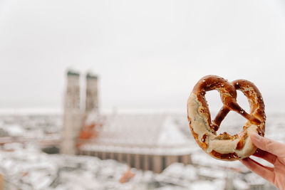 Close-up of hand holding pretzel on munich background