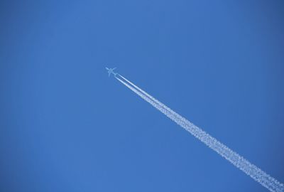 Low angle view of airplane flying against clear blue sky