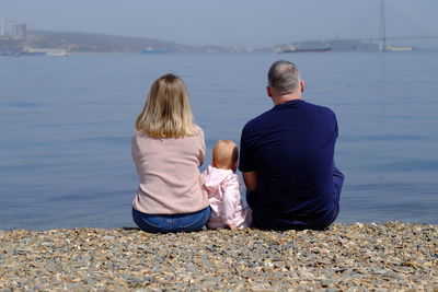 Rear view of woman and man sitting on beach