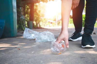 Low section of woman picking garbage on road