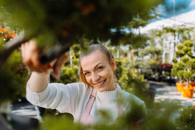 Portrait of young woman standing by plants
