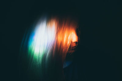 Close-up of woman against black background