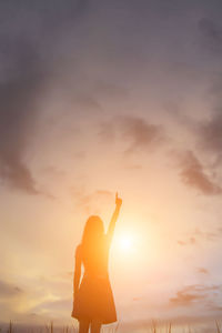 Silhouette woman standing against sky during sunset