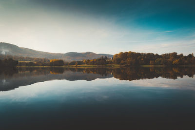 Scenic view of lake by trees against sky