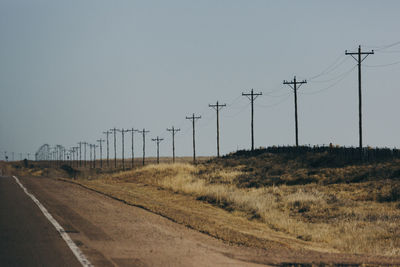 Electricity pylons on field against clear sky