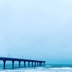 Bridge over calm sea against sky