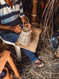 Low section of man sitting on wicker basket