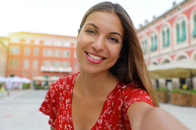 Portrait of smiling woman standing against buildings in town