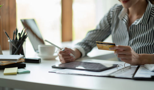 Midsection of woman using mobile phone on table